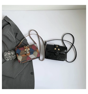 Detail view of colorful patchwork and black glossy mini crossbody bags on white background