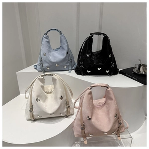 Détail de quatre sacs fourre-tout en daim avec charms papillon argentés en plusieurs couleurs