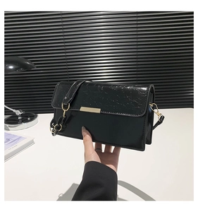 Détail de la texture en cuir PU noir brillant avec boucle en métal doré sur le sac à main