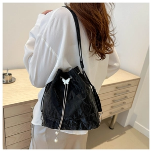 Détail du sac seau noir plissé avec boucle papillon et élégants pompons en perles