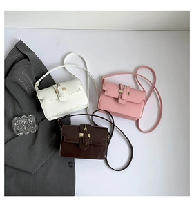 Three minimalist flap crossbody bags in white, pink, and coffee leather with gold hardware