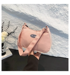 Detail of pink nylon crescent bag featuring side white piping and an oval brand logo