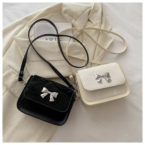Détail de sacs bandoulière carrés avec papillon métallique en noir et beige classique