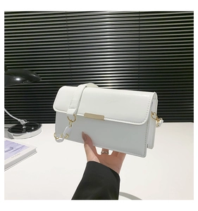 Détail d'un sac à bandoulière en cuir blanc brillant avec boucle en métal doré minimaliste