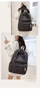 Side and back view of a black floral canvas backpack with white webbing straps