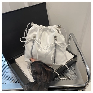 Détail du sac seau blanc avec fermeture à cordon, zips métalliques et nœuds déco