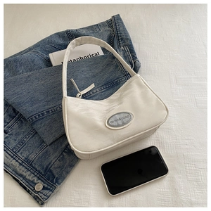Chic white crinkled patent leather shoulder bag styled on a white textured fabric