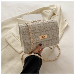 Détail du tissu en tweed et du fermoir doré sur le sac à bandoulière blanc élégant