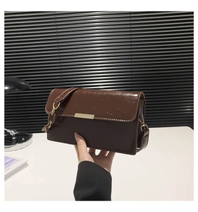 Détail d'un sac à bandoulière en similicuir marron avec garniture dorée et chaîne ambre