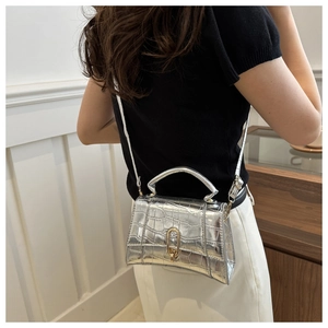 Detail of silver crocodile-embossed trapezoid bag with U-shaped metallic buckle clasp