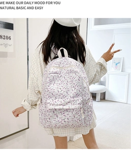 Back view of a minimalist white floral backpack worn by a model in a bright room