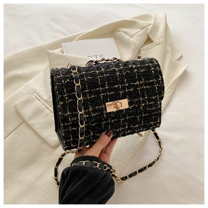 Détail du sac bandoulière en tweed noir avec fils métalliques dorés et fermoir rotatif