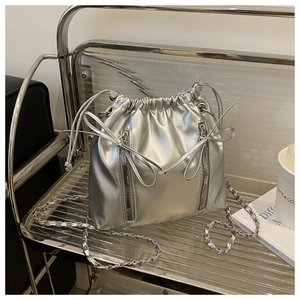 Détail du sac seau argenté avec nœud décoratif et doubles fermetures éclair