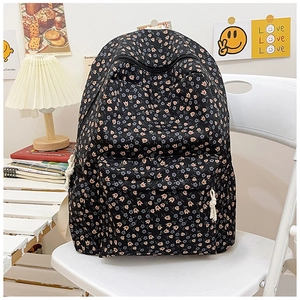 Detail of a black student backpack featuring pink tulip floral patterns on a white chair