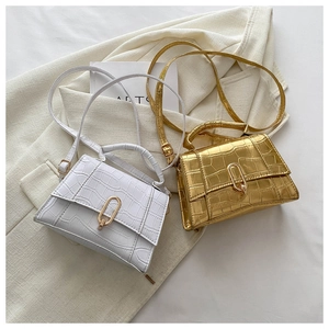Detail view of crocodile-patterned mini bags in white and gold with metal clasp