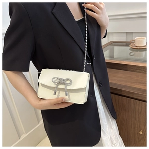 Chic cream crossbody bag featuring a sparkling rhinestone bow and silver ball chain
