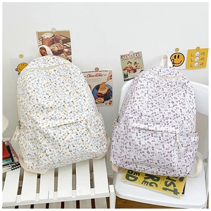 Close-up of canvas backpacks with small floral patterns in yellow and purple colors
