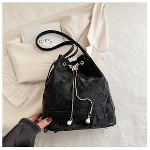 Détail du sac seau noir avec boucle papillon en métal et accents de perles blanches