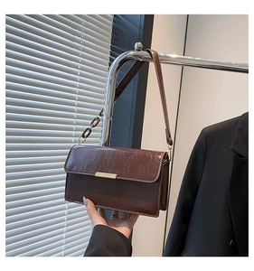 Gros plan sur le cuir PU marron foncé plissé et la boucle métallique du sac à bandoulière