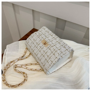 Détail du tissu en tweed et de la bandoulière chaîne dorée sur un petit sac à rabat