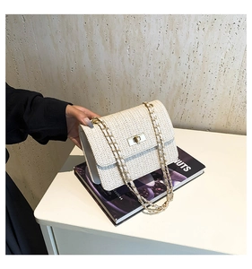 Détail d'un sac bandoulière tissé crème avec chaîne dorée et texture à motif en V
