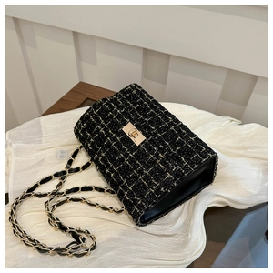 Détail du tissu en tweed noir et blanc avec fermoir doré et bandoulière en chaîne