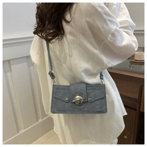 Blue denim mini crossbody bag with silver planet buckle shown on a model in white shirt
