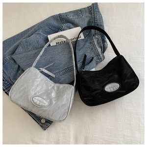Detail of minimalist nylon shoulder bags in black and silver with pleated texture on denim