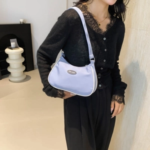 Lavender crescent nylon hobo bag with white trim and slim shoulder strap on model