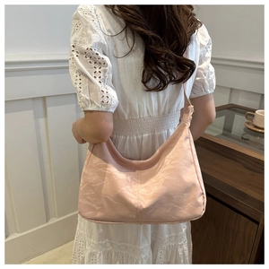 Detail of light pink pleated hobo bag texture and wide strap on model with lace dress