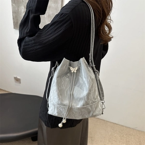 Sac seau argenté avec bandoulière chaîne et texture plissée métallique porté par mannequin