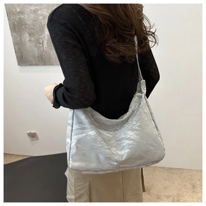Silver metallic tote bag with wrinkled texture and wide shoulder strap shown on model