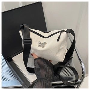 Detailansicht der weißen Tasche mit Silber-Schmetterling und schwarzem Gurt