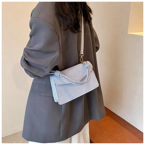 Detail of light blue denim texture bag with knot handle and gold hardware hook