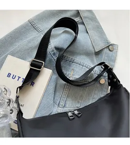 Detail of black nylon crossbody bag featuring dual zippers and adjustable fabric strap