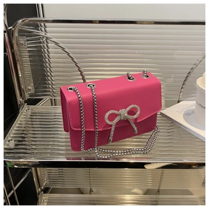 Detailed shot of pink leather bag featuring a silver rhinestone bow and chain strap