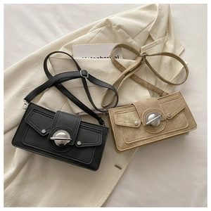 Black and khaki flap crossbody bags with silver metal buckle on a beige blazer