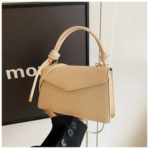 Detail of beige woven handbag featuring a cotton rope handle and gold metal rings