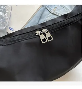Detail of smooth silver double zippers on a black nylon crossbody bag fabric