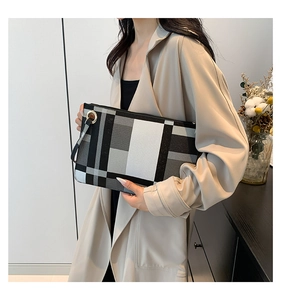 Chic black and white plaid envelope clutch bag shown in a minimalist lifestyle setting