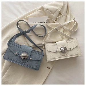 Detail view of retro crossbody bags in blue denim and beige leather with round metal locks