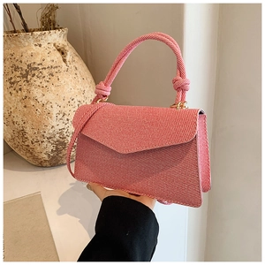 Detail of red and white striped crossbody bag with unique knotted handle and flap closure