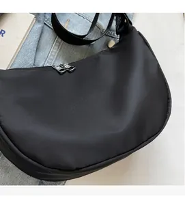 Close-up of black nylon crescent bag featuring double zippers and durable woven strap