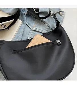 Detailed view of the front zipper pocket on a black crescent bag showing storage capacity