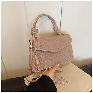 Close-up of beige woven envelope bag with knot handle and golden metal clasp