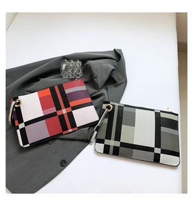 Detail view of colorful geometric plaid clutch bags with gold zipper and wrist straps
