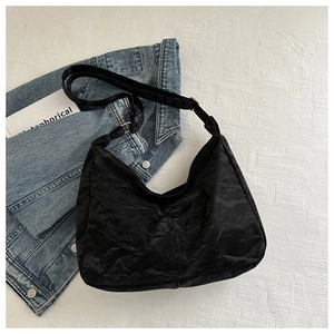 Detail view of the black pleated crescent bag with adjustable wide shoulder strap design