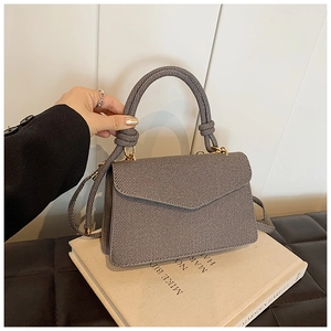 Detail of dark grey crossbody bag with twill texture and decorative knot handle detail
