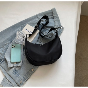 Macro view of nylon crescent bag texture and adjustable strap on denim jacket