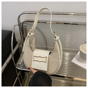 Detail of woven straw and cream leather shoulder bag with golden metallic clasp